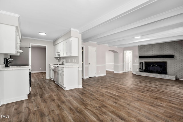 kitchen with dishwasher, a brick fireplace, ornamental molding, dark hardwood / wood-style flooring, and white cabinetry