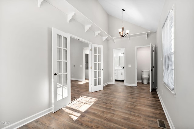 unfurnished bedroom featuring ensuite bath, french doors, an inviting chandelier, dark hardwood / wood-style floors, and vaulted ceiling