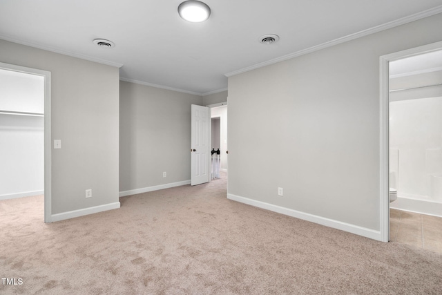 unfurnished bedroom featuring light carpet, a walk in closet, crown molding, and connected bathroom