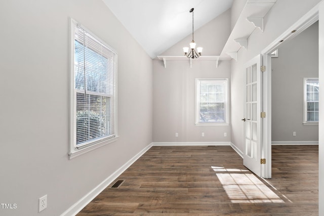 unfurnished room featuring a chandelier, dark hardwood / wood-style floors, vaulted ceiling, and a wealth of natural light