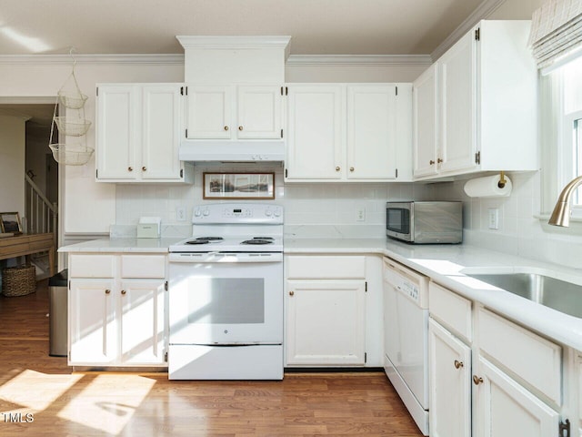 kitchen featuring white appliances, backsplash, white cabinets, ornamental molding, and sink