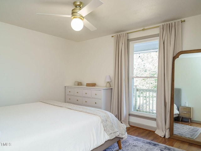 bedroom featuring hardwood / wood-style flooring, ceiling fan, and multiple windows