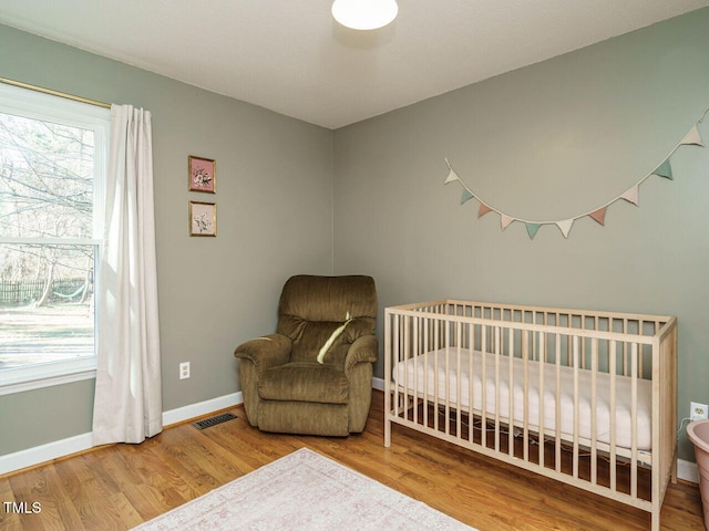 bedroom featuring a nursery area and hardwood / wood-style flooring