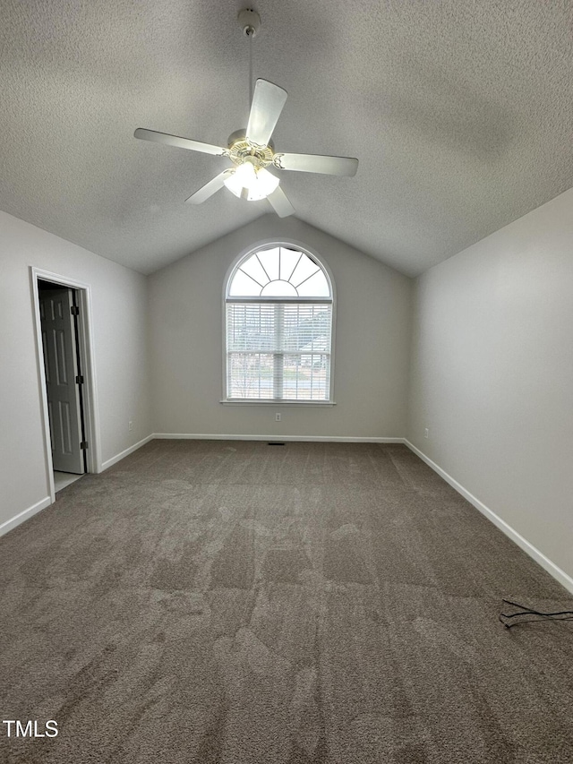 empty room featuring ceiling fan, lofted ceiling, carpet floors, and a textured ceiling