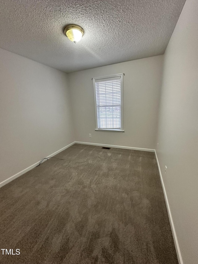 unfurnished room with a textured ceiling and dark colored carpet