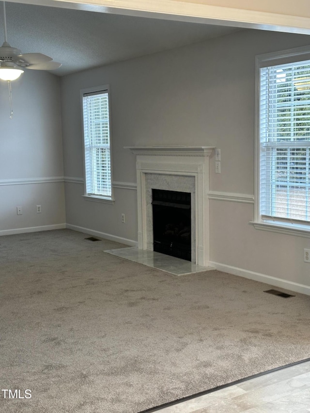 unfurnished living room featuring ceiling fan, a healthy amount of sunlight, and a fireplace