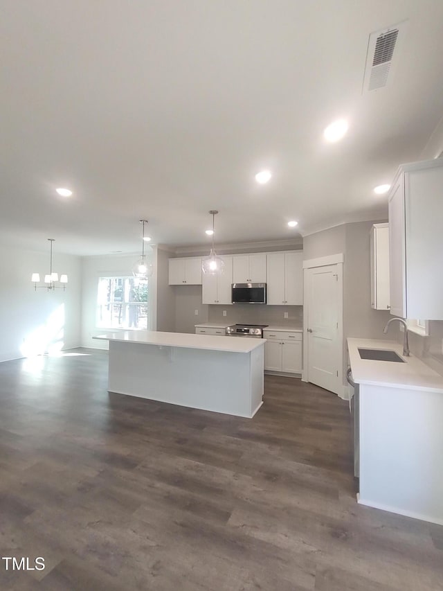 kitchen with stainless steel appliances, visible vents, white cabinets, a sink, and a kitchen island