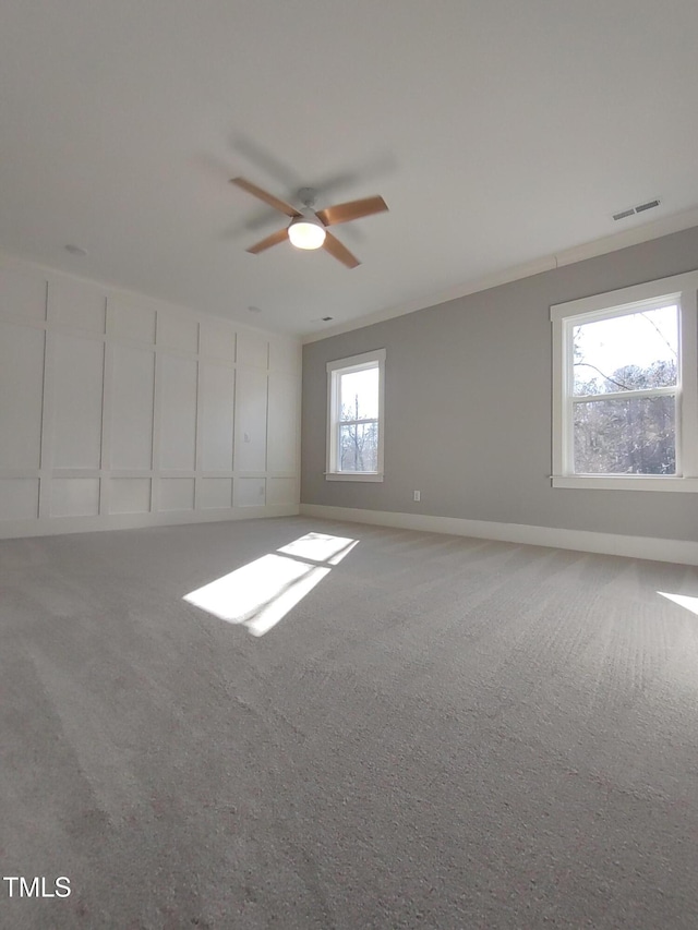 carpeted empty room featuring a ceiling fan, visible vents, and baseboards