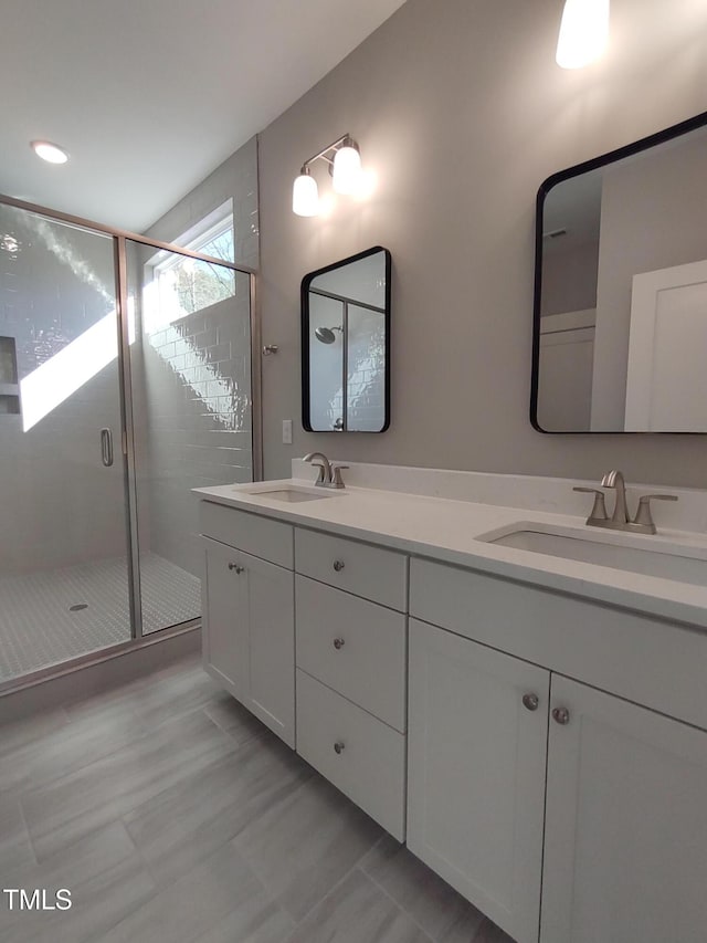 bathroom with double vanity, a stall shower, and a sink