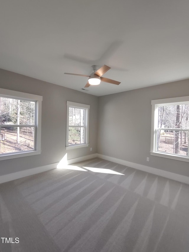 carpeted spare room featuring baseboards and a ceiling fan