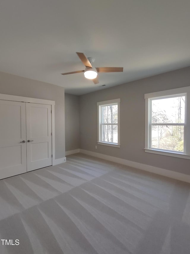 interior space featuring light colored carpet, ceiling fan, and baseboards