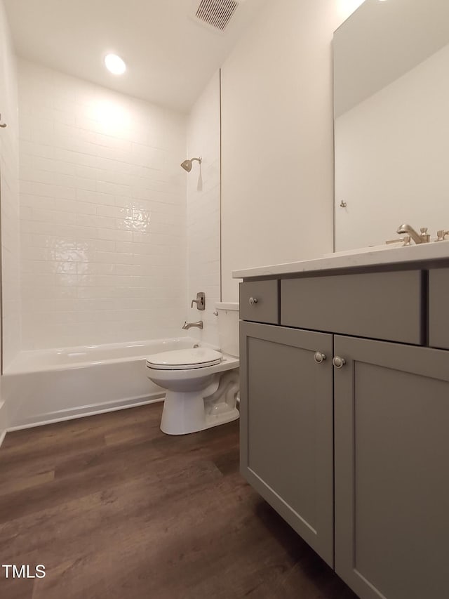 full bathroom featuring toilet, wood finished floors, vanity, visible vents, and tub / shower combination