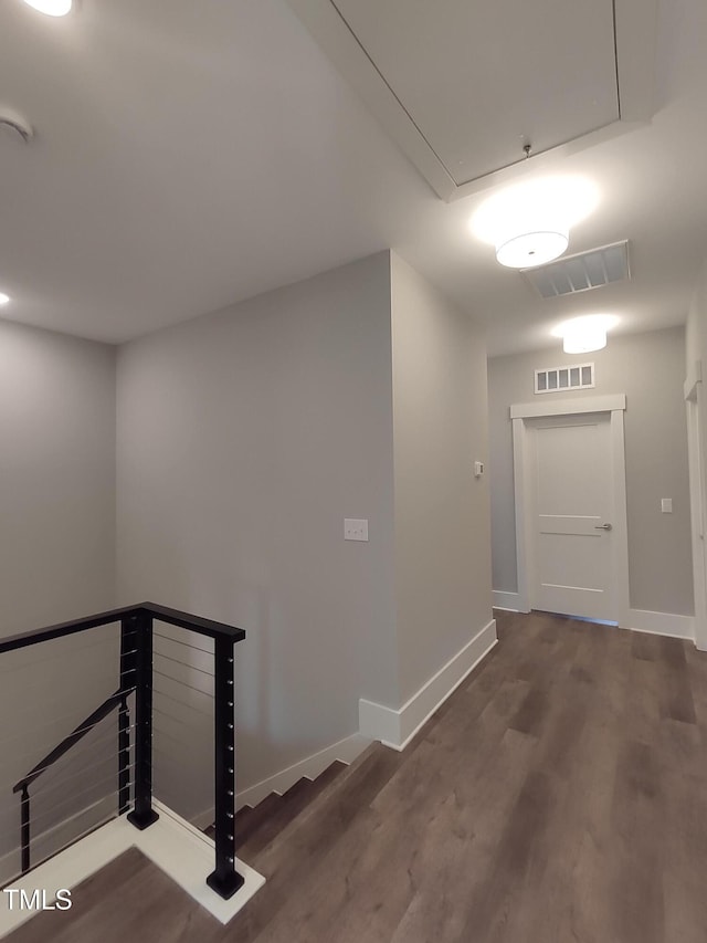 hall with attic access, visible vents, wood finished floors, and an upstairs landing