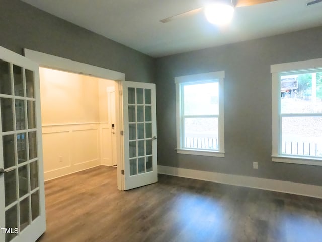 empty room with french doors, dark wood-style flooring, a decorative wall, a ceiling fan, and baseboards