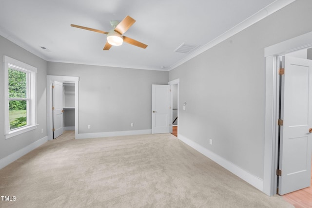 632 Angus Ct, Sanford, NC 27332 - unfurnished bedroom with a walk in closet, ornamental molding, baseboards, light colored carpet, and ceiling fan