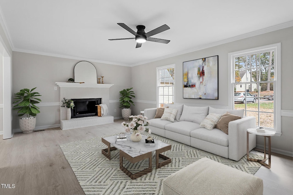 living room featuring light hardwood / wood-style floors, a brick fireplace, ceiling fan, and ornamental molding