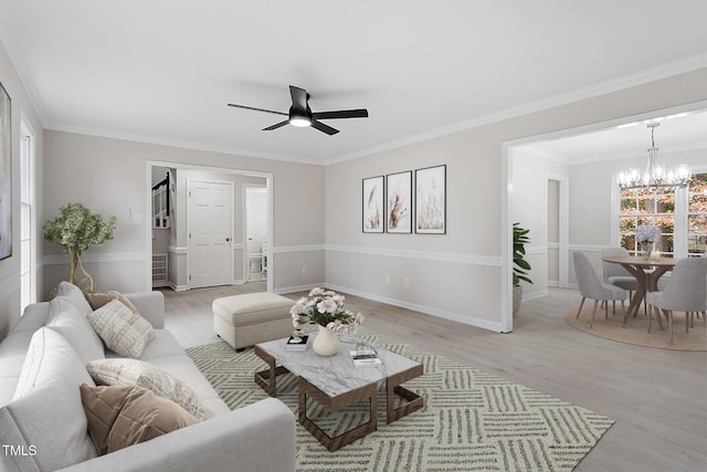 living room with ceiling fan with notable chandelier, light hardwood / wood-style floors, a wealth of natural light, and crown molding