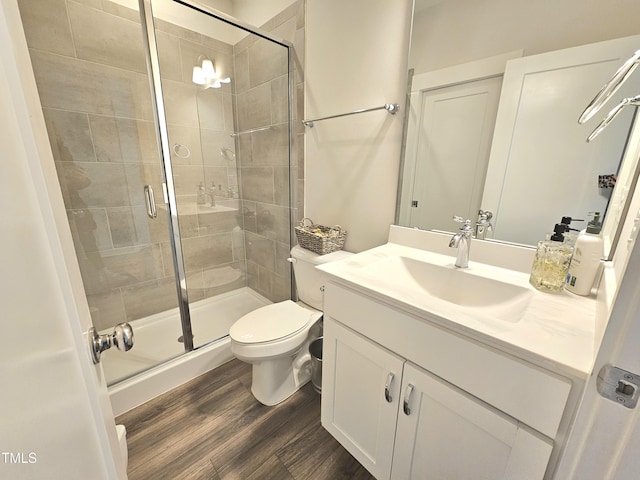 bathroom featuring vanity, hardwood / wood-style flooring, toilet, and a shower with door