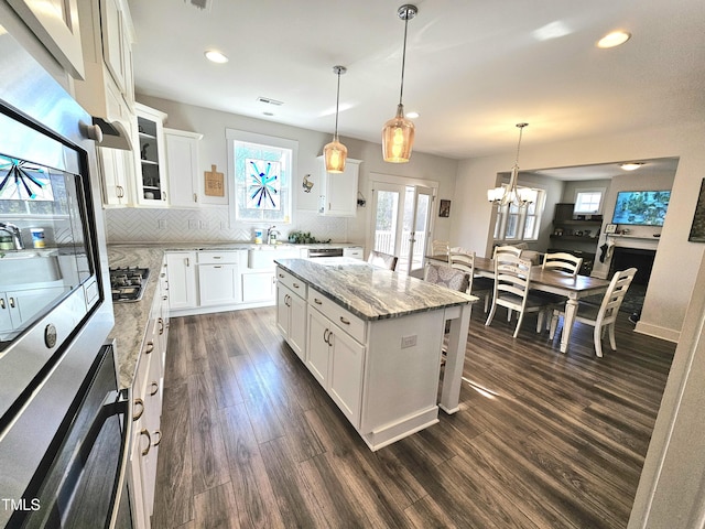 kitchen with white cabinets, oven, a kitchen island, and hanging light fixtures