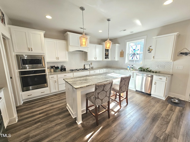 kitchen featuring white cabinetry, a kitchen island, stainless steel appliances, and light stone counters