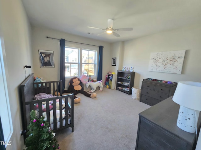 carpeted bedroom with ceiling fan and a crib