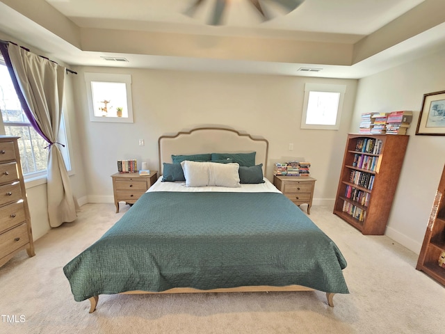 carpeted bedroom featuring ceiling fan and a raised ceiling