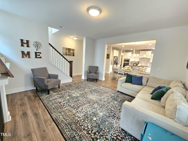 living room featuring stairs, wood finished floors, visible vents, and baseboards