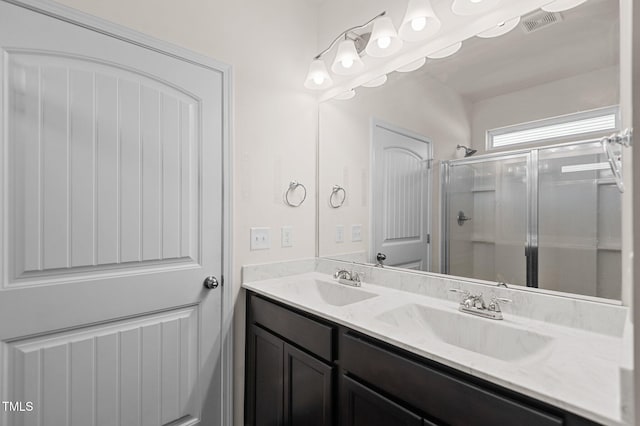 bathroom featuring a shower with door and vanity