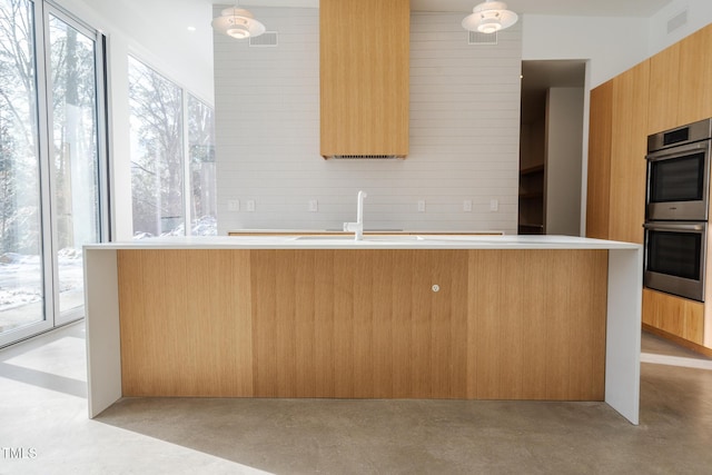 kitchen with double oven, sink, and pendant lighting