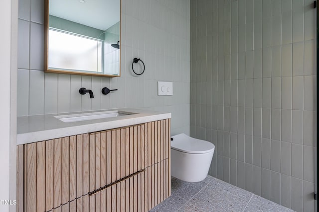 bathroom featuring vanity, tile walls, and toilet