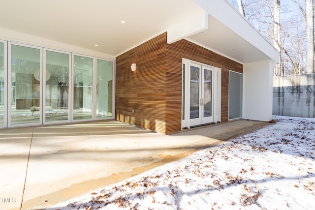 snow covered property entrance with a patio and french doors