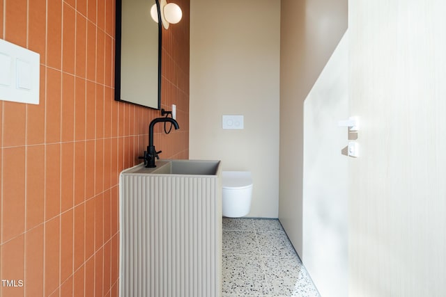 bathroom featuring tile walls, sink, and toilet