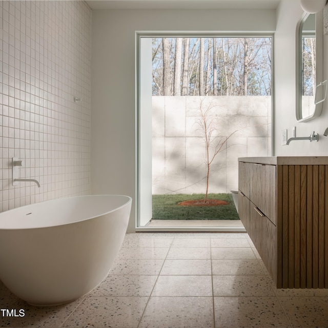 bathroom featuring a washtub, vanity, and tile walls