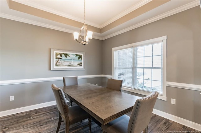 dining area featuring a notable chandelier, crown molding, dark hardwood / wood-style flooring, and a tray ceiling