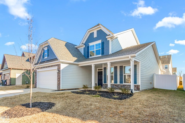 view of front of home with covered porch, a front lawn, and a garage