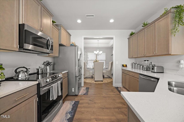 kitchen with pendant lighting, dark wood-type flooring, a notable chandelier, and appliances with stainless steel finishes