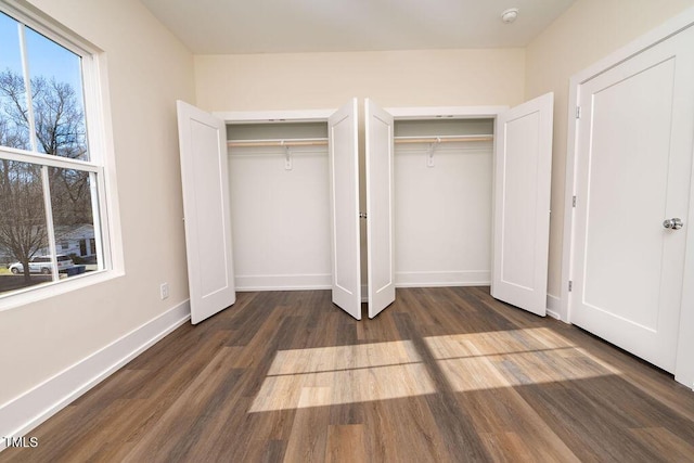 unfurnished bedroom featuring two closets and dark wood-type flooring