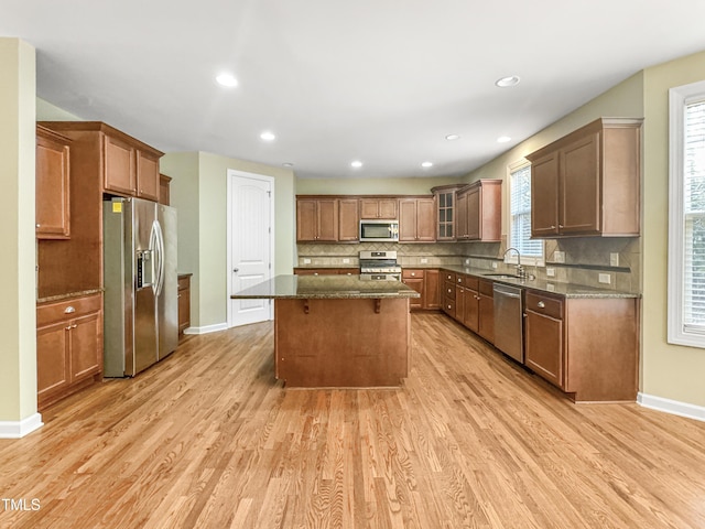 kitchen featuring sink, a center island, tasteful backsplash, appliances with stainless steel finishes, and light wood-type flooring