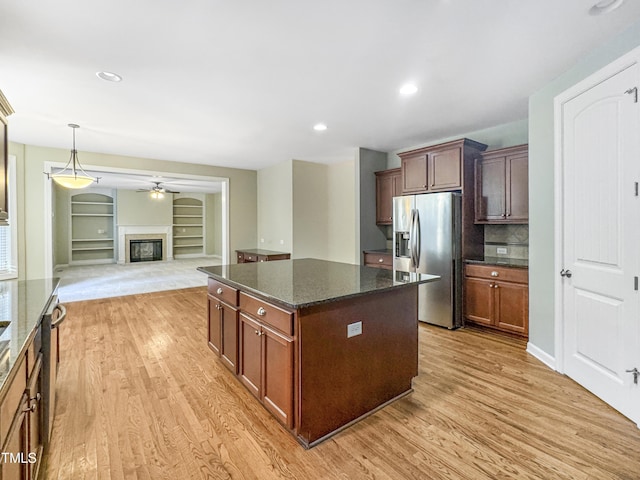 kitchen with a center island, built in shelves, stainless steel fridge, dark stone countertops, and light hardwood / wood-style floors