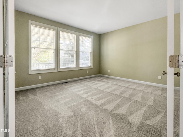 empty room featuring carpet, visible vents, and baseboards