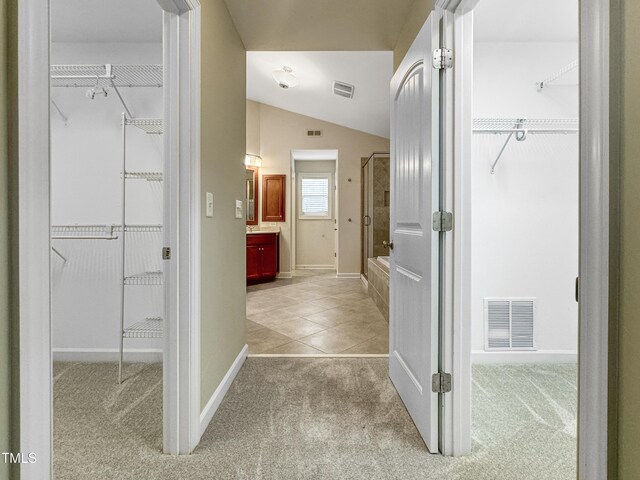 bathroom featuring lofted ceiling, a shower with door, and visible vents