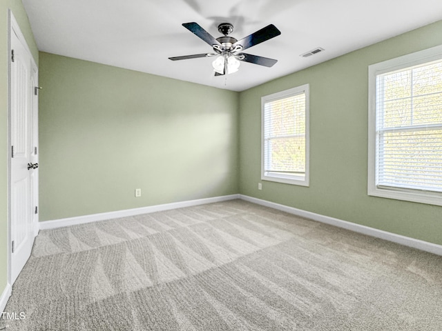 carpeted empty room with a ceiling fan, visible vents, and baseboards