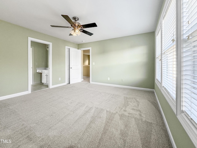 unfurnished bedroom with carpet floors, connected bathroom, a ceiling fan, and baseboards