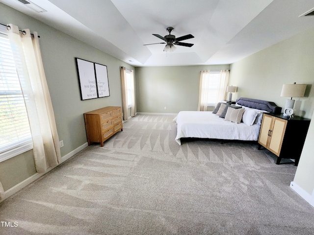 bedroom featuring light carpet, a raised ceiling, visible vents, and baseboards