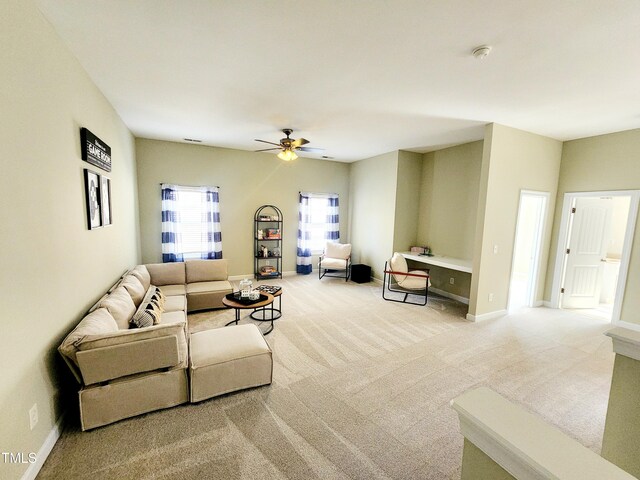 living room with ceiling fan, baseboards, and light colored carpet