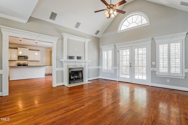 unfurnished living room with french doors, wood finished floors, a fireplace with flush hearth, and visible vents