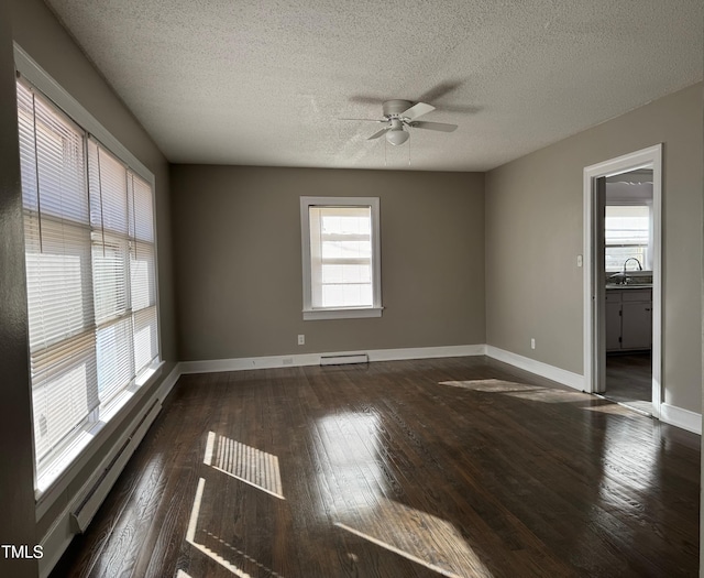 unfurnished room featuring baseboard heating, ceiling fan, dark hardwood / wood-style flooring, and a textured ceiling