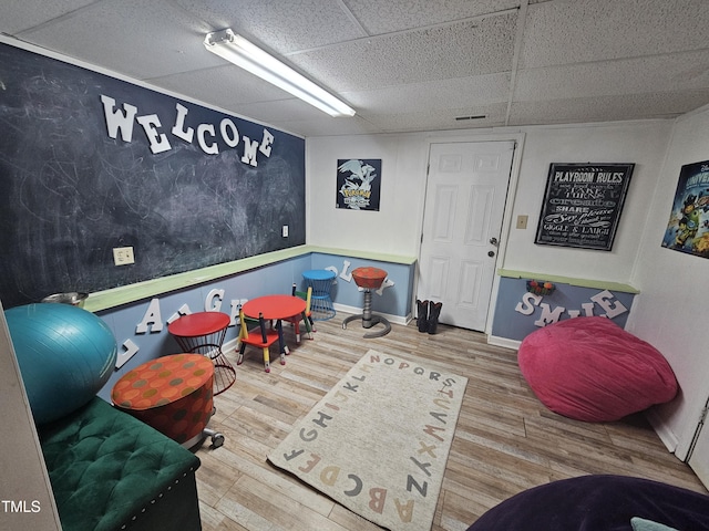 rec room featuring a paneled ceiling, baseboards, and wood finished floors