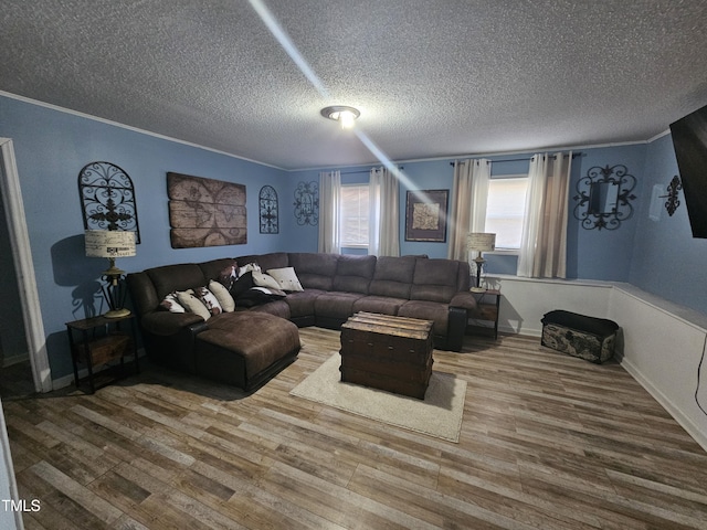 living room with baseboards, a textured ceiling, ornamental molding, and wood finished floors