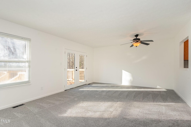 carpeted empty room with a ceiling fan, french doors, visible vents, and baseboards